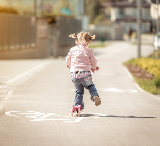 little  girl riding her scooter - Fotografie, Obrázek