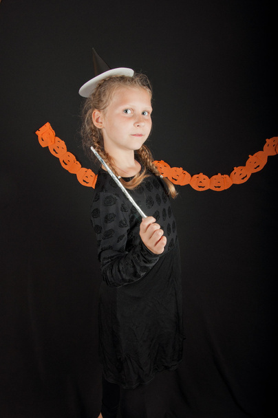 Fille en costume d'Halloween avec baguette magique sur fond noir
 - Photo, image