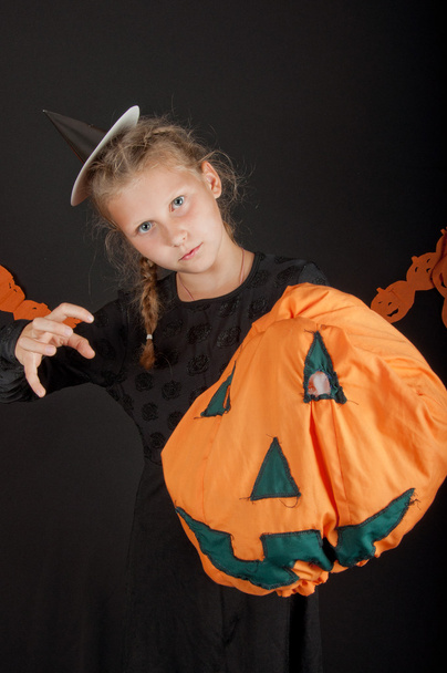 Girl in halloween costume with pumpkin on black background - Foto, imagen