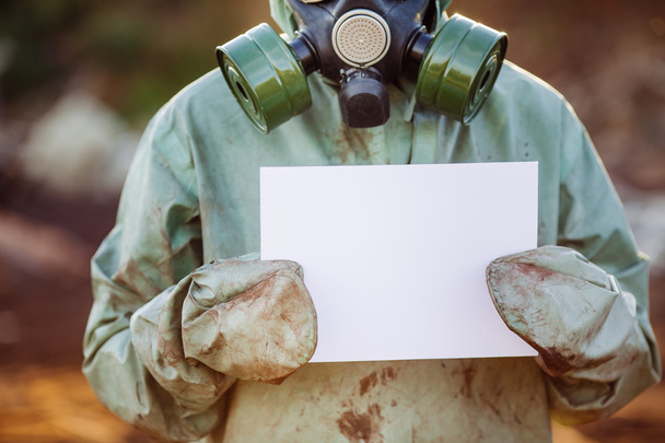 Man with gas mask and green military clothes Showing Paper On Cl - Foto, Imagen