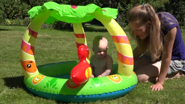 mother care baby daughter first time in small child pool with water. 4K - Footage, Video