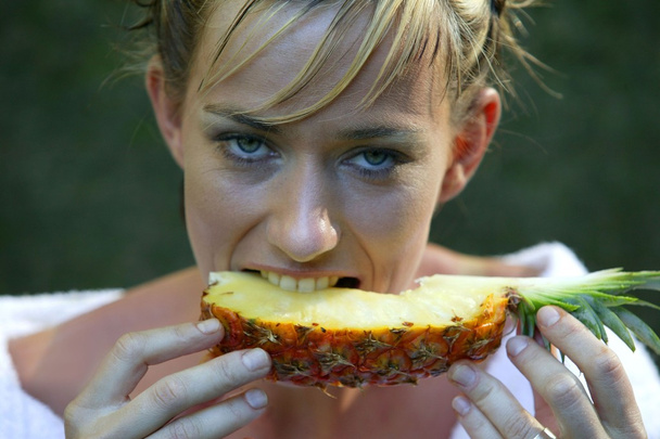 Woman eating a slice of pineapple - Fotó, kép