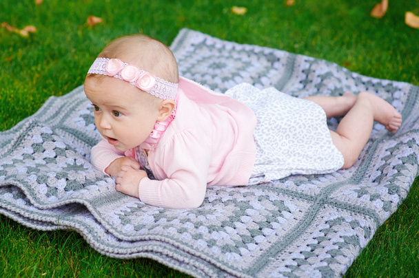 beautiful little baby girl is lying on a plaid blanket - Фото, зображення