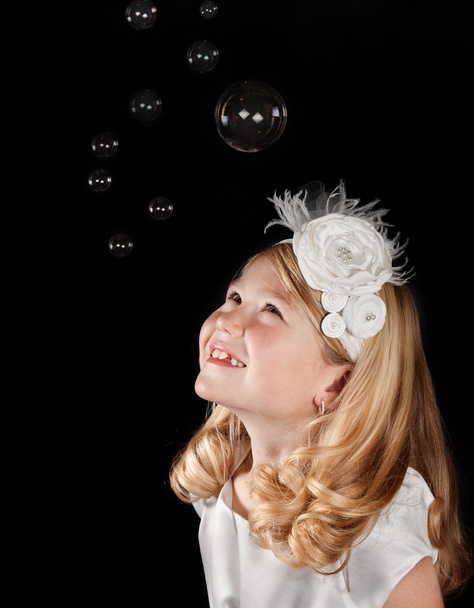 Girl Dressed in White Looking up at Bubbles - Foto, Imagen