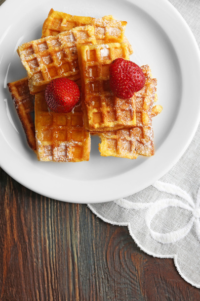Sweet homemade waffles with strawberries  on plate, on table background - Fotó, kép