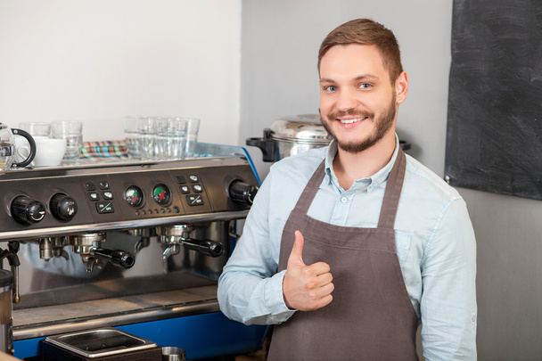Cheerful young male cafe owner is gesturing positively - Fotoğraf, Görsel