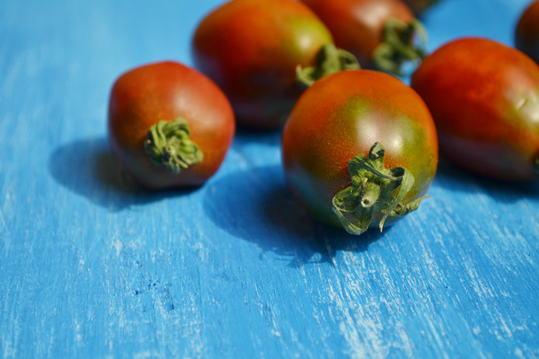 Tomates vermelhos escuros grandes no fundo azul brilhante
 - Foto, Imagem