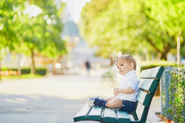 Adorable little toddler sitting on the bench - Фото, изображение
