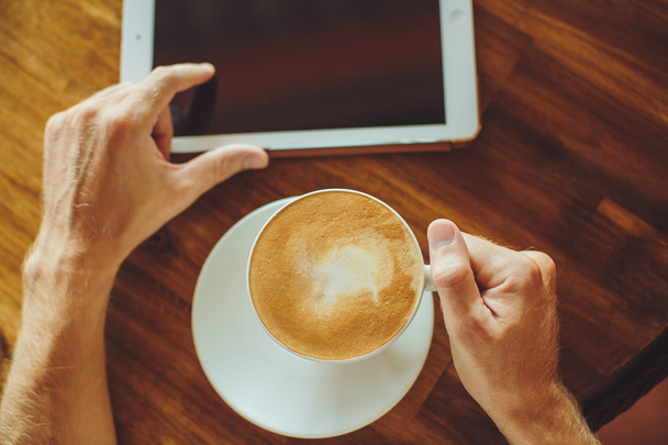 Men's hands hold the tablet with coffee - Foto, Imagen