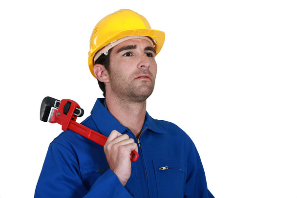 Pensive electrician holding adjustable spanner - 写真・画像
