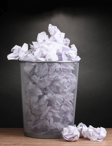 Metal trash bin from paper on wooden floor on gray background - Фото, зображення