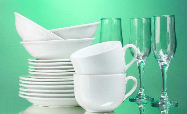 Clean plates, cups and glasses on green background - Zdjęcie, obraz