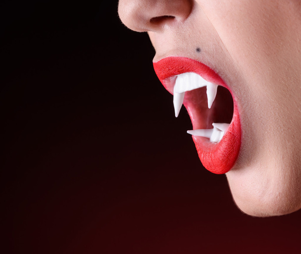 Close up shot of woman vamire mouth with white fangs - Fotó, kép