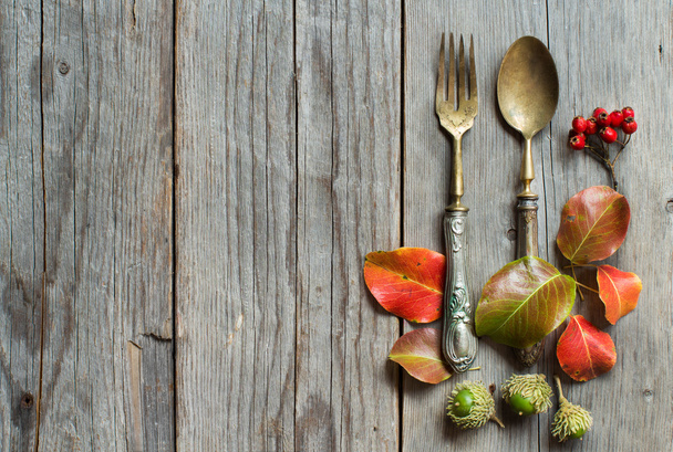 Vintage vork en mes met najaar bladeren op hout - Foto, afbeelding