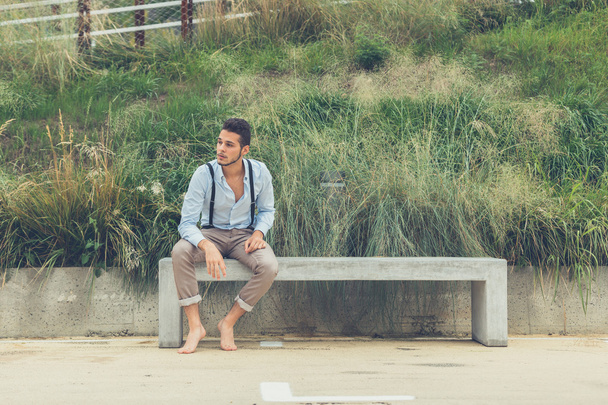 Young handsome man sitting on a concrete bench - Fotografie, Obrázek