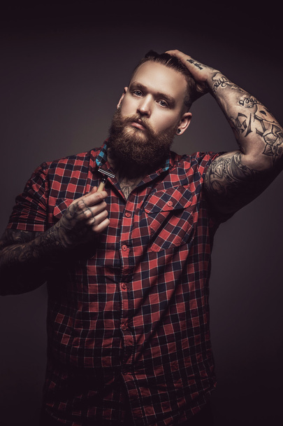 Hombre tatuado con barba en camiseta roja
. - Foto, imagen
