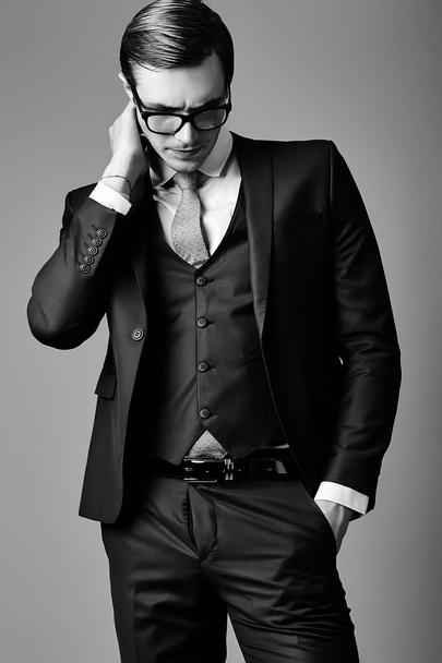 Nuori tyylikäs komea liikemies miesmalli puku ja muodikas lasit, poseeraa studiossa
 - Valokuva, kuva