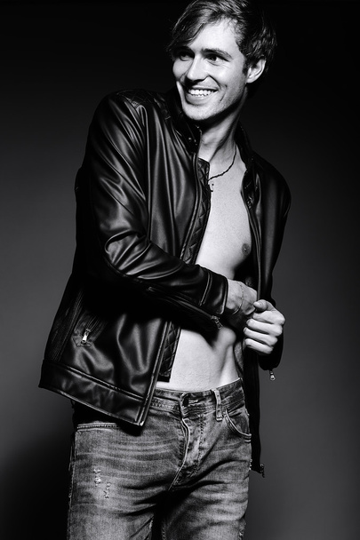 Young handsome muscled fit male model man in leather jacket posing in studio showing his abdominal muscles - Fotoğraf, Görsel