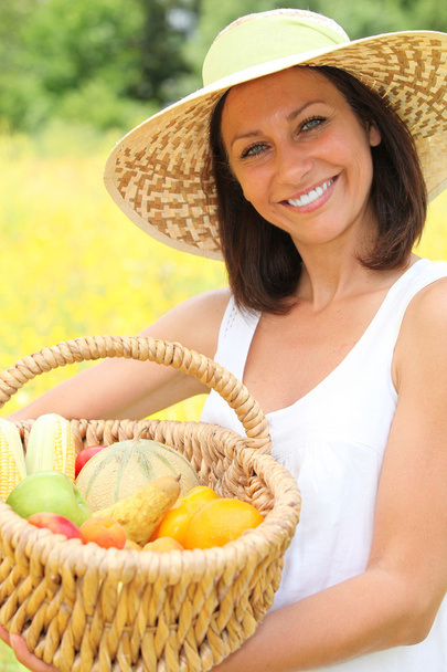 Woman carrying fruits in basket - Фото, изображение