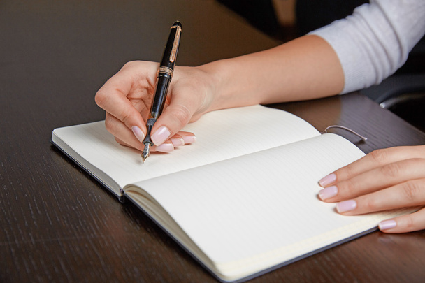 Femme écrivant dans un livre avec stylo
 - Photo, image