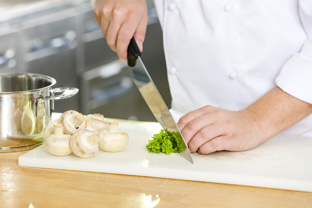 Professional chef cutting parley and mushrooms - 写真・画像