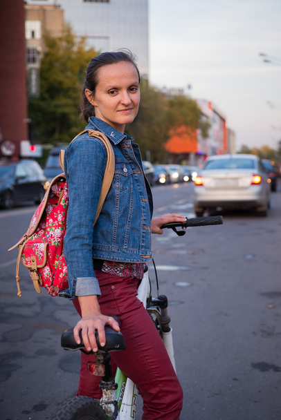 Young woman standing with a bicycle on the way to work in the city center - Fotografie, Obrázek