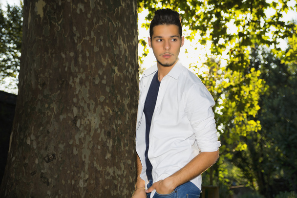 Attractive young man in park next to trees - Foto, afbeelding