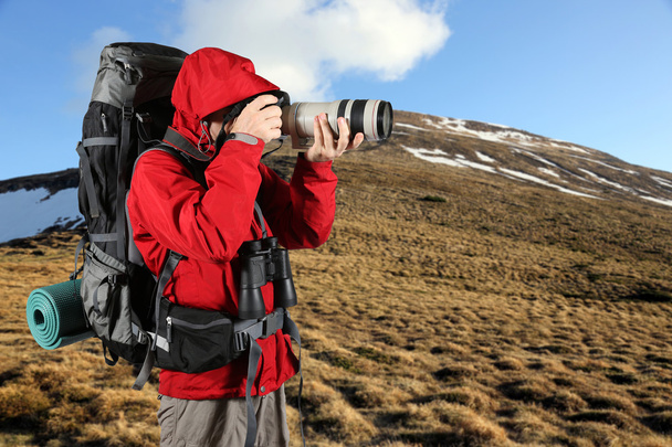 turista in giacca rossa con uno zaino grigio scattare foto
 - Foto, immagini