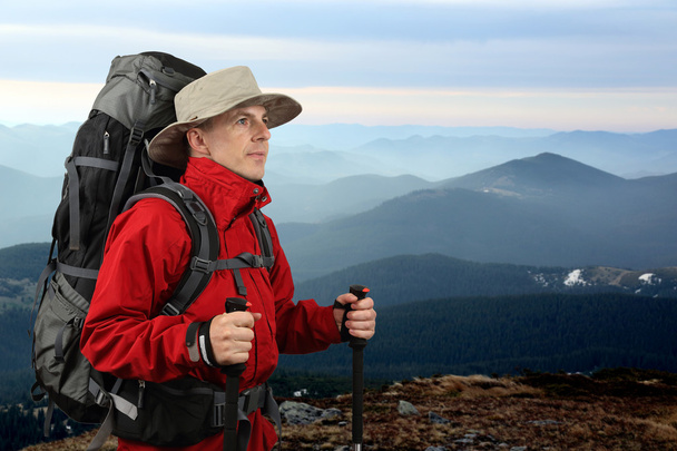dotato di viaggiatore in giacca rossa con bastoni da trekking guarda i
 - Foto, immagini