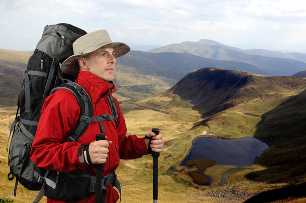 equipped with traveler in a red jacket with Hiking poles looks i - Photo, Image
