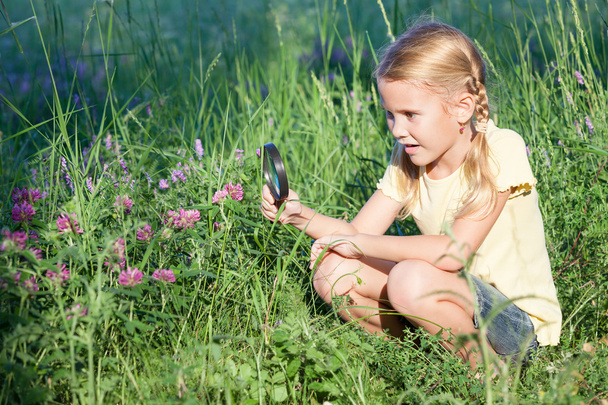Happy little girl exploring nature with magnifying glass - Foto, Bild