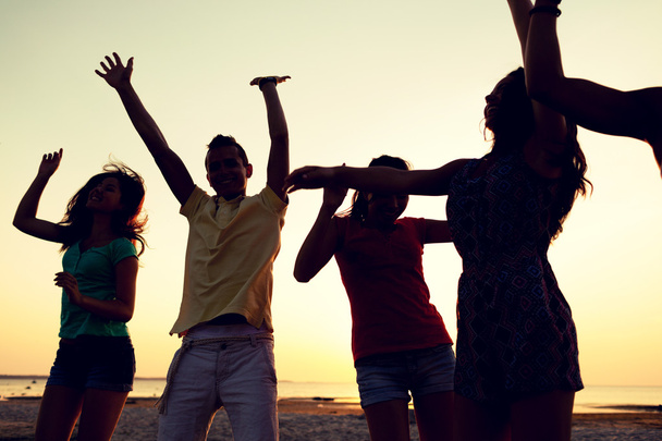 lachende vrienden dansen op zomer strand - Foto, afbeelding