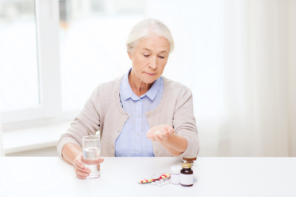 senior woman with water and medicine at home - 写真・画像