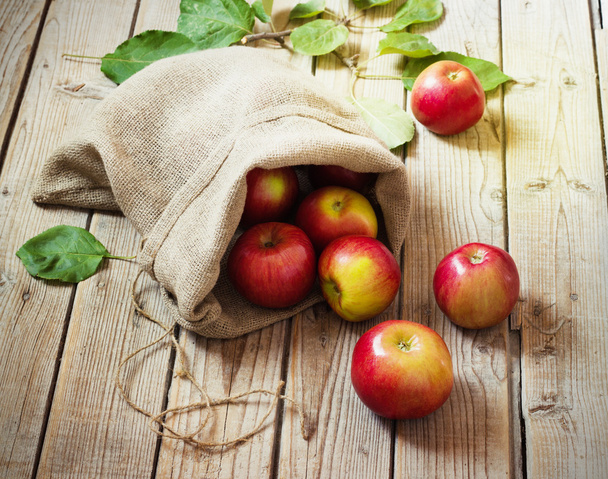 Ripe red apples in a bag on wooden background - Foto, imagen