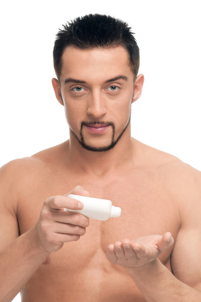 Young man applying cream. Cosmetic - Zdjęcie, obraz