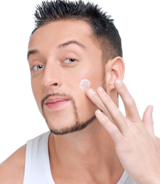 Handsome man applying male creme on face - Fotoğraf, Görsel