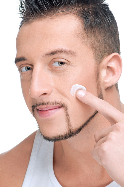 Handsome man applying male creme on face - Foto, Imagen