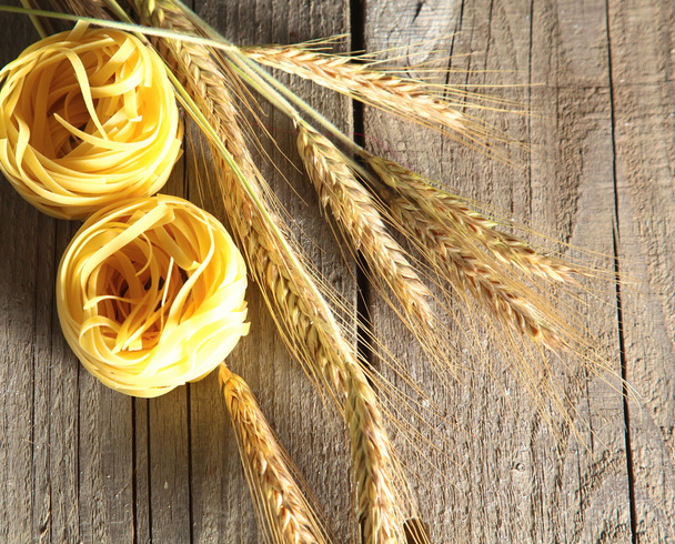 Ruwe huisgemaakte pasta en ingrediënten voor pasta op houten achtergrond - Foto, afbeelding