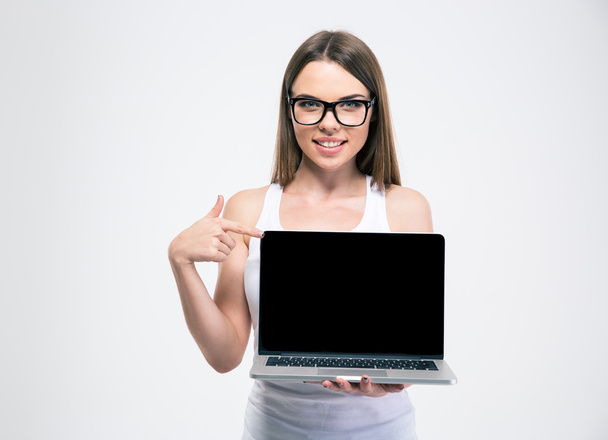 Smiling girl pointing finger on a blank laptop screen - Фото, изображение