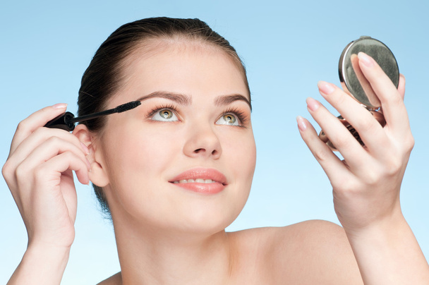Beautiful young adult woman applying cosmetic mascara brush - Foto, imagen
