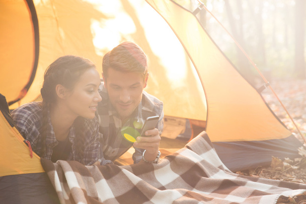Couple using smartphone in the tent - Foto, afbeelding