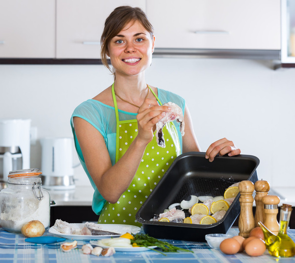 housewife putting pieces of white fish in tray - Foto, Bild
