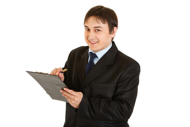 Smiling young businessman making notes in document - Foto, Imagen