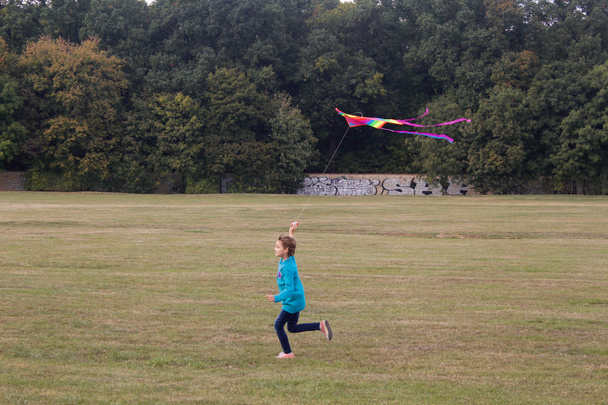 Kleines Mädchen läuft mit fliegendem Drachen - Foto, Bild