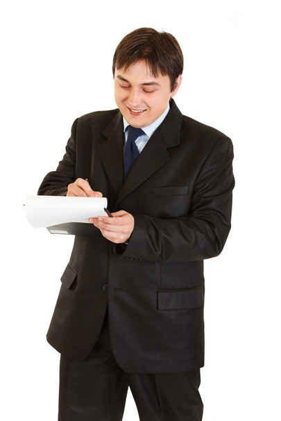Smiling young businessman making notes in document - Foto, Imagen