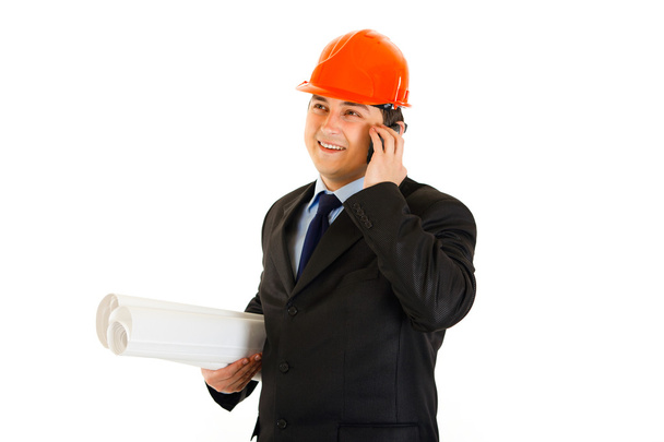Hombre de negocios sonriente en casco que sostiene planes de construcción y habla en el móvil
 - Foto, imagen