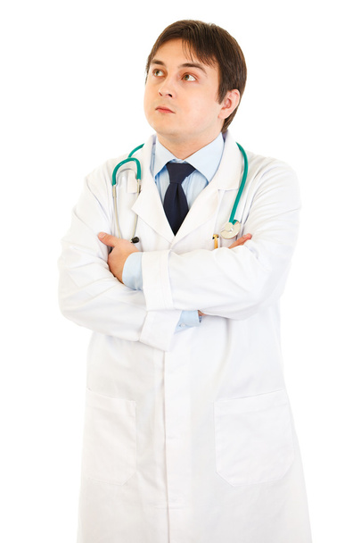 Thoughtful doctor with crossed arms on chest looking up at copy space - Foto, Imagen