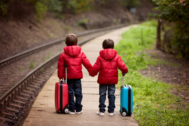 Two boys on a railway station, waiting for the train with suitca - Foto, Bild