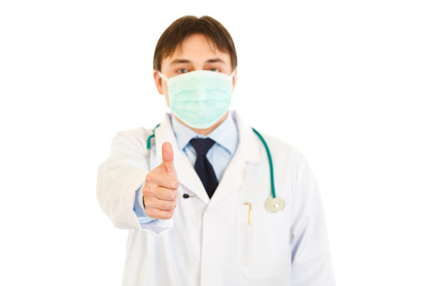 Medical doctor with mask on face showing thumbs up gesture - 写真・画像