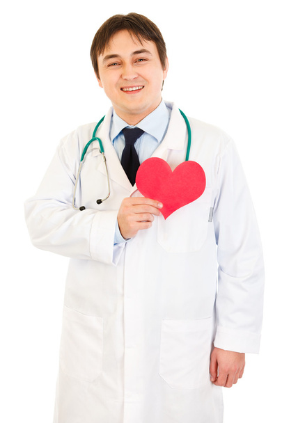 glimlachend arts papier hart houden in de buurt van borst - Foto, afbeelding